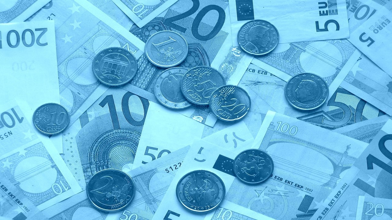 Euro novčanice i kovanice raznih apoena raspoređene po površini s plavim tonom.