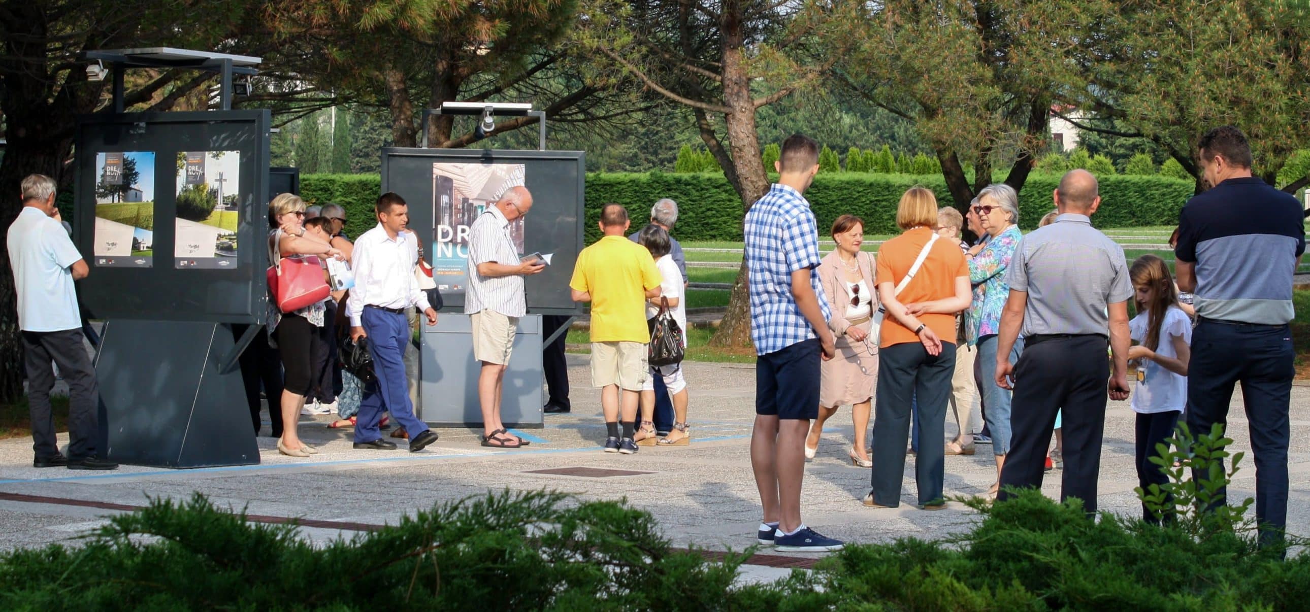 Posjetitelji na otvorenom razgledavaju izložbene panele postavljene na uređenom platou groblja.