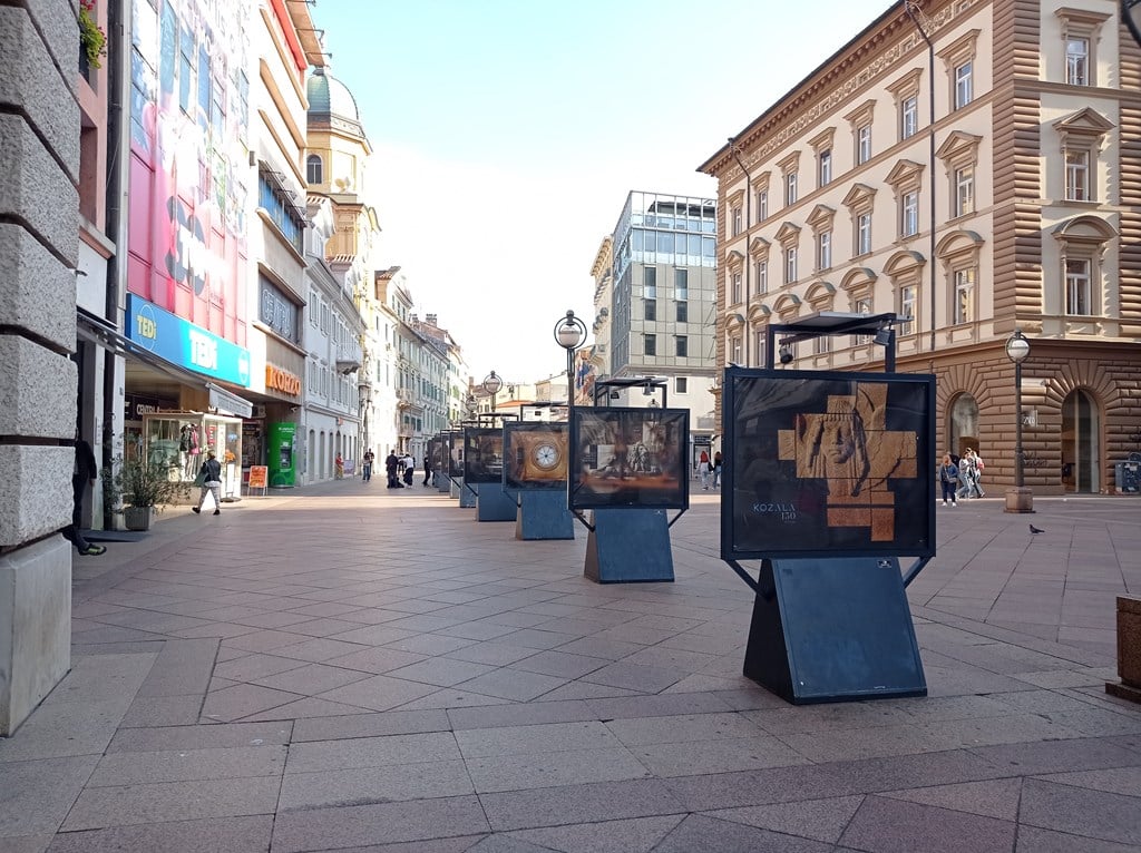Izložbeni panoi o povijesti groblja Kozala postavljeni duž riječkog Korza okruženi zgradama i prolaznicima.